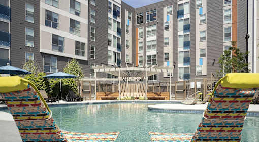 A pool area with a water slide and two lounge chairs.