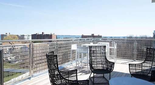 A balcony with a table and chairs overlooking a cityscape.