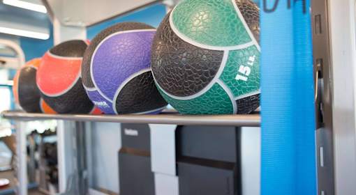 A row of colorful exercise balls are lined up on a shelf.