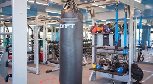 A gym with a punching bag and a rack of kettlebells.