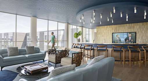 A modern living room with a bar area and a person standing by the window.