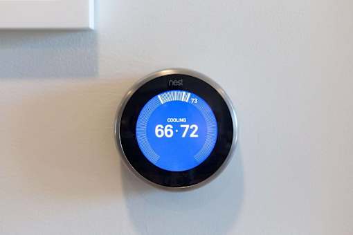 A nest thermostat shows the temperature is cooling from 73 to 66-72.