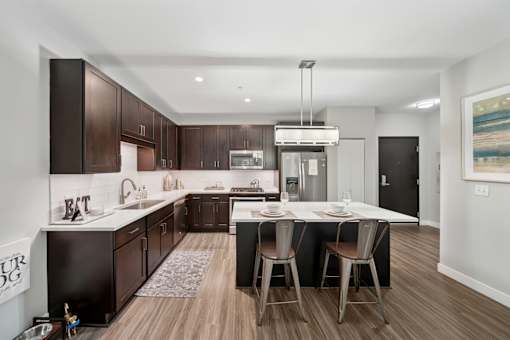 A modern kitchen with dark brown cabinets and a white island.