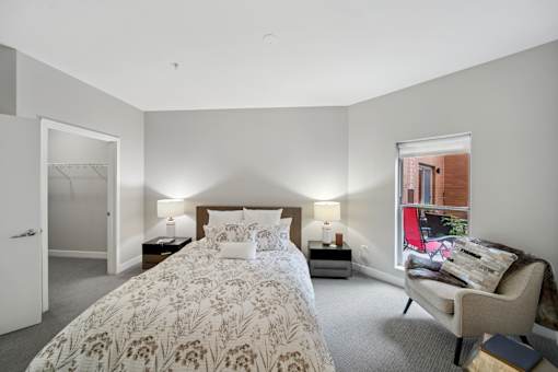 A bedroom with a large bed and a chair.