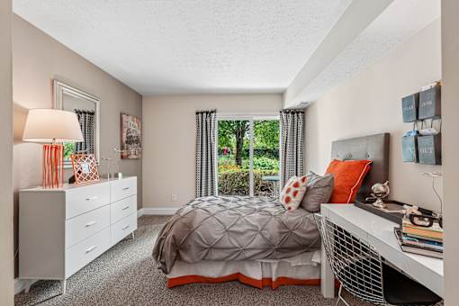 A bedroom with a bed, nightstand, and window with curtains.