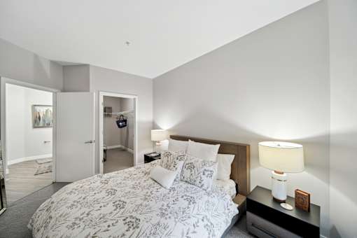 A bedroom with a large bed and a nightstand with a lamp.