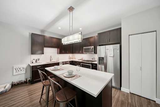 A modern kitchen with dark brown cabinets and white countertops.