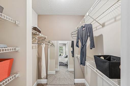 A walk-in closet with clothes hanging and shelves.