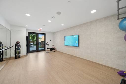 A room with a wooden floor and a television on the wall.