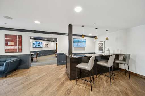 A modern kitchen with a bar area and chairs.