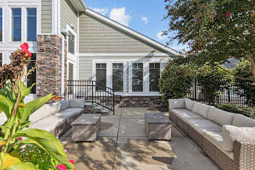 a patio with couches and tables in front of a house