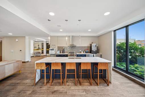 A modern kitchen with a large island and wooden chairs.