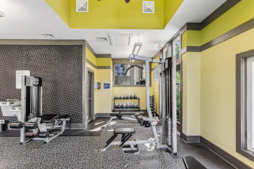 a gym with weights machines and yellow walls and a window