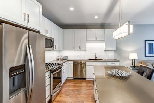 A modern kitchen with a stainless steel refrigerator and wooden flooring.