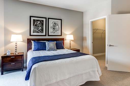 A bedroom with a bed, nightstands, and two wall lamps.