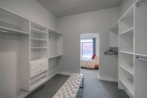 A walk-in closet with white shelving and drawers.