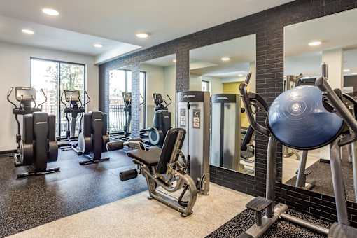 A gym with a variety of equipment including treadmills, weights, and exercise machines.