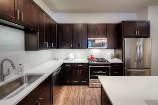 A kitchen with dark brown cabinets and a white counter top.