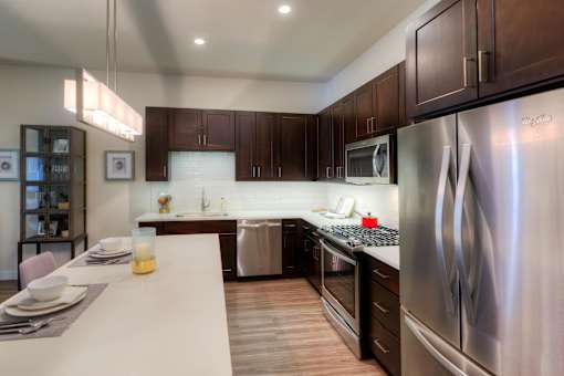 A modern kitchen with dark wood cabinets and stainless steel appliances.