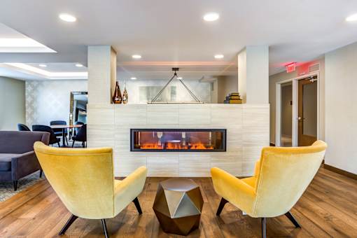 A modern living room with a fireplace and two yellow chairs.