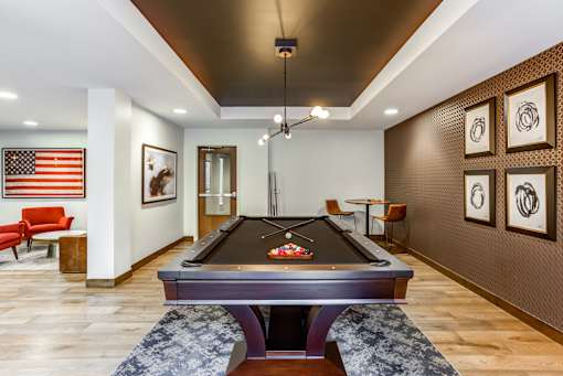 A pool table in a room with a red chair and an American flag.