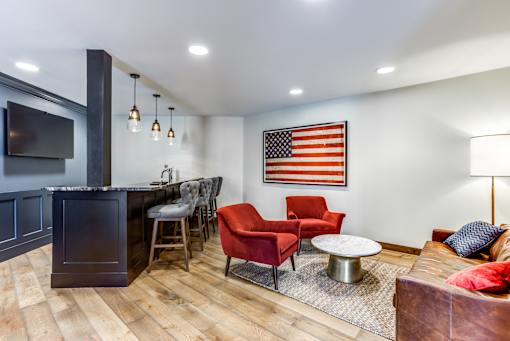 A living room with a bar area and a large American flag on the wall.