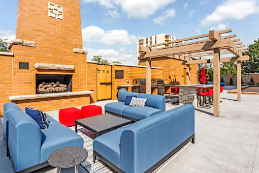 A patio with a blue couch and a fireplace.