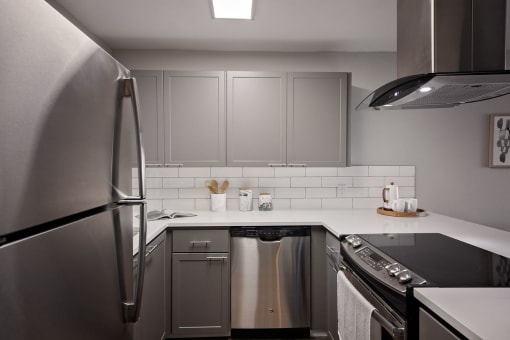 Apartments for Rent in Mountain Park - MiLO at Mountain Park - Chef-Grade Kitchen, with White Countertops and Backsplash, Grey Cabinetry, Black Electric Stovetop, and a Refrigerator.