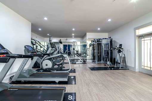 A spacious gym with a variety of equipment including treadmills, elliptical machines, and weight machines.