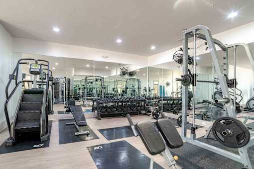 A spacious gym with a variety of equipment including treadmills, weight benches, and dumbbells.