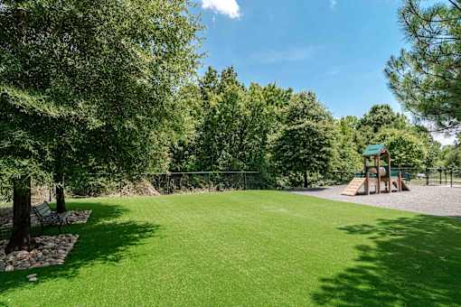 A playground with a green lawn and trees.