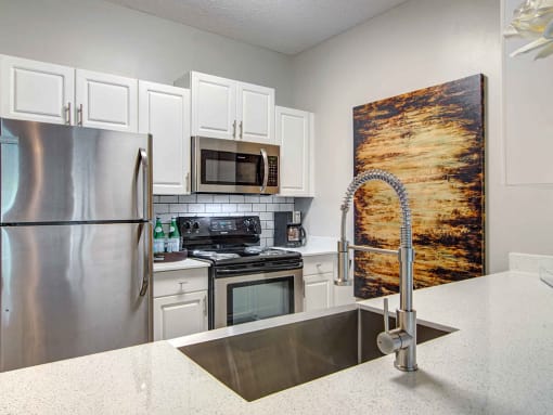 Alpharetta Apartments – The Ascent at Windward – Luxury kitchen with white cabinets, stainless-steel appliances and granite countertops