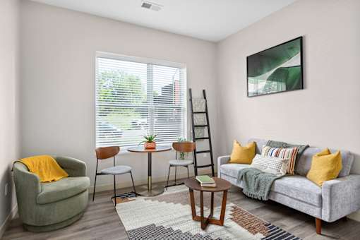 A living room with a grey couch, a green armchair, a small table, and a rug.