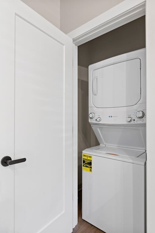 A white dryer is in a white closet.