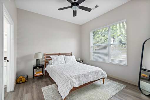 A bedroom with a bed, nightstand, and window.