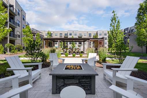 A patio with a fire pit and chairs.