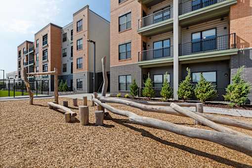 Apartment buildings with balconies and a playground in front.