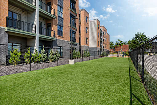A row of apartment buildings with a green lawn in front.