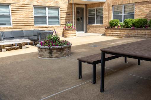 a patio with a wooden table and bench in front of a building