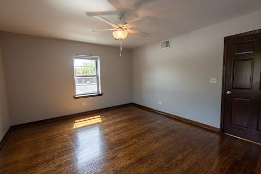 an empty room with a ceiling fan and a window
