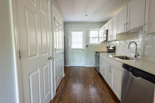 a kitchen with white cabinets and a stainless steel dishwasher