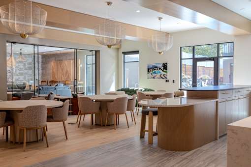 a dining room with tables and chairs and a kitchen and living room