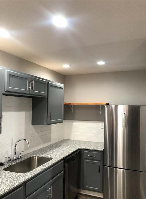 A kitchen with a stainless steel refrigerator and black cabinets.