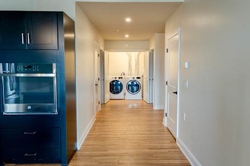 A modern kitchen with a dark blue fridge and wooden floors.
