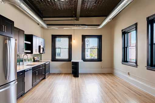 A kitchen with wooden floors and black cabinets.