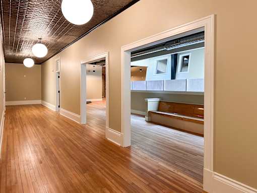 A hallway with wood floors and a bench.