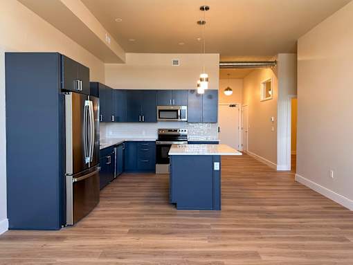A kitchen with dark blue cabinets and a wooden floor.