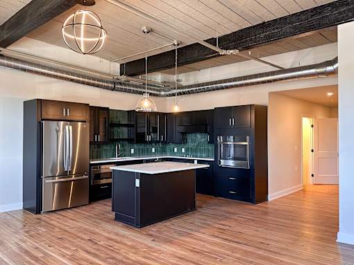 A modern kitchen with dark wood floors and stainless steel appliances.