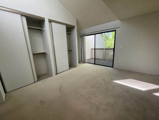 an empty room with a sliding glass door and a balcony