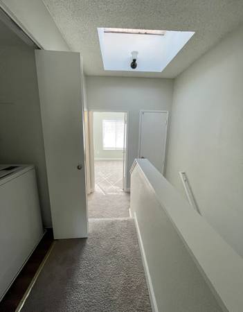 a long white hallway with a skylight in the ceiling